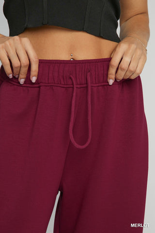 Wine color sweatpants with drawstring shown on woman at waist 