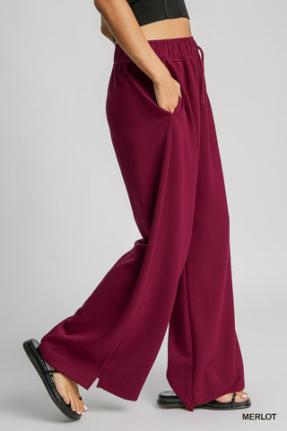 Side view of Wine color sweatpants with drawstring and wide leg shown on woman from waist down