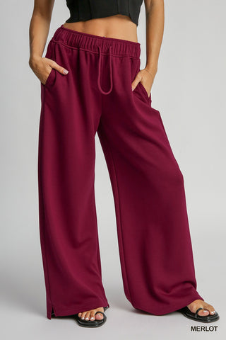 Wine color sweatpants with drawstring and wide leg shown on woman from waist down.